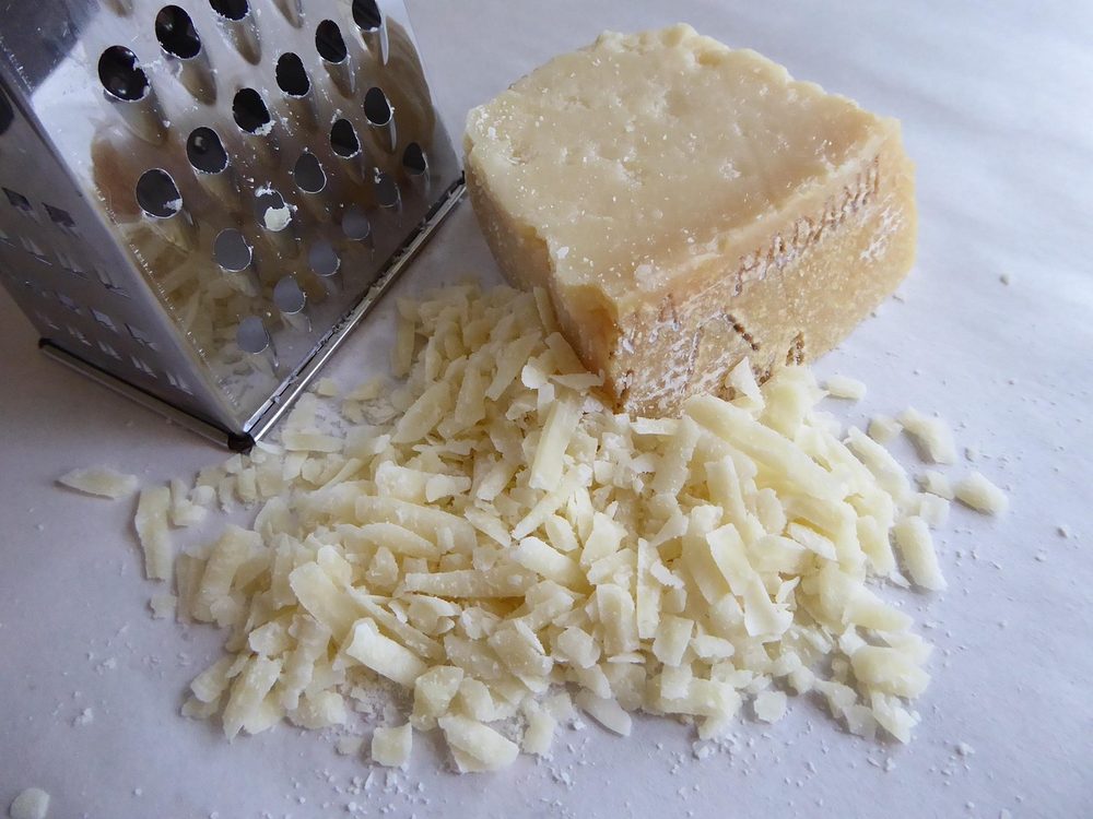 Stuk Parmezaanse kaas met een rasp en geraspte kaas